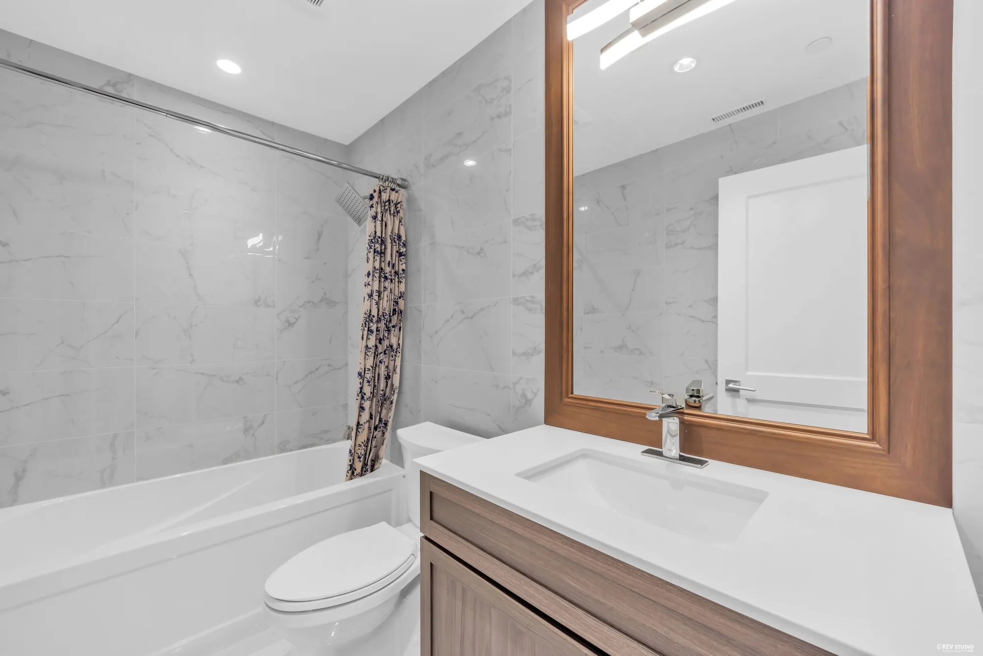 The lower-floor bathroom with a tub and shower, marble walls and a stone vanity