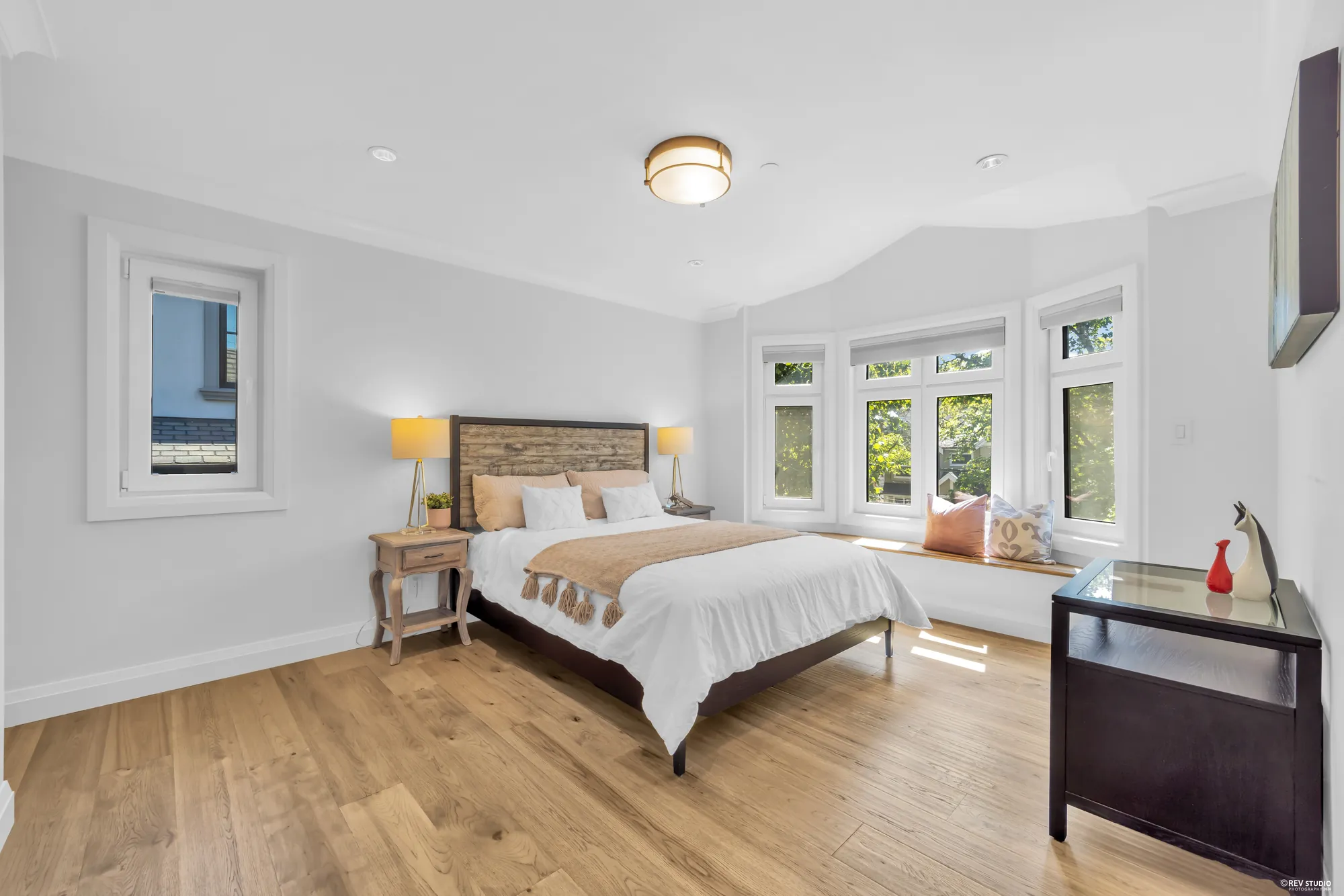 A bedroom on the upper floor with a bay of three windows behind the bed