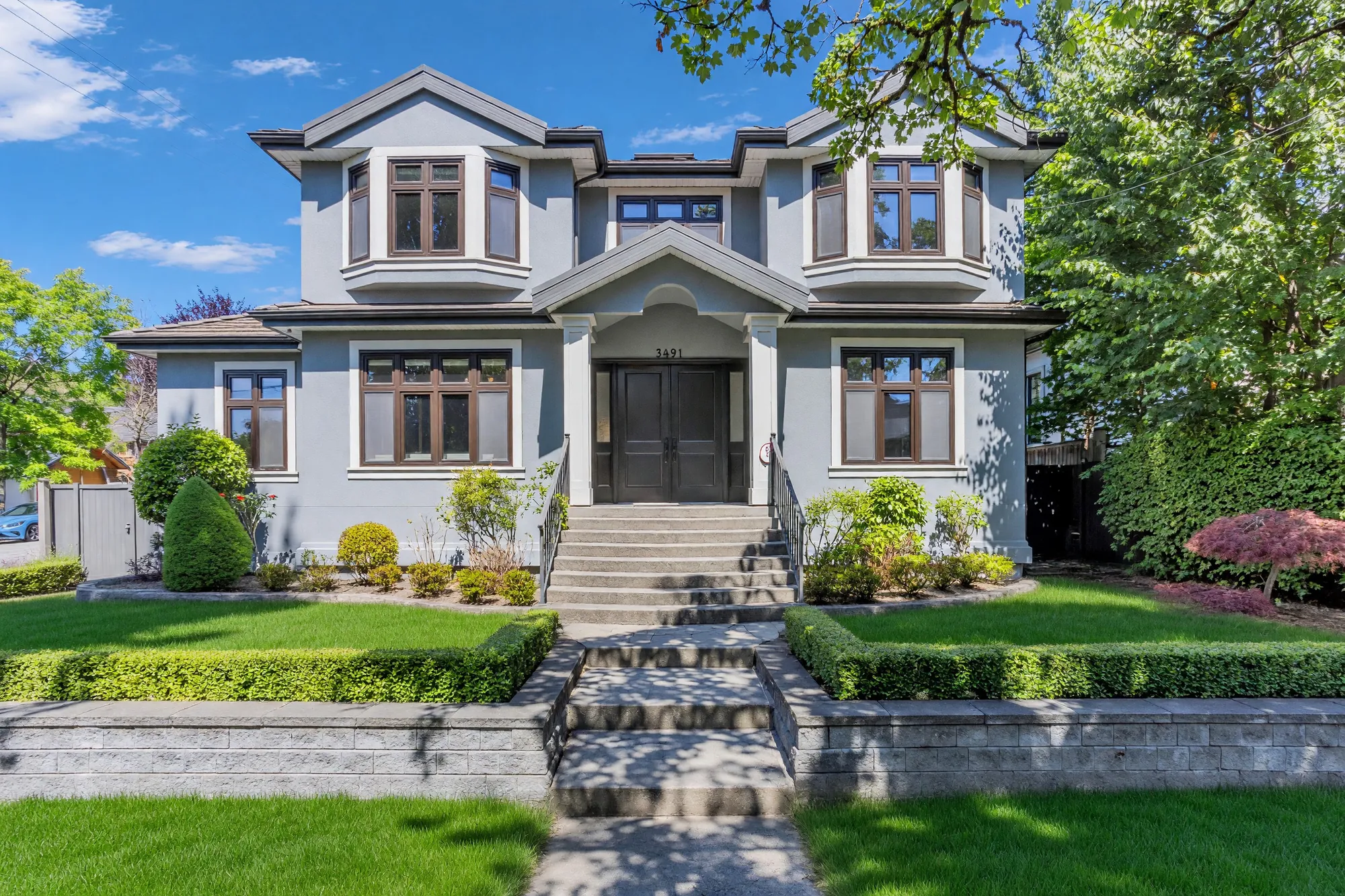 The south front of 3491 West 40th Avenue in daylight, the entrance steps rising between clipped hedges