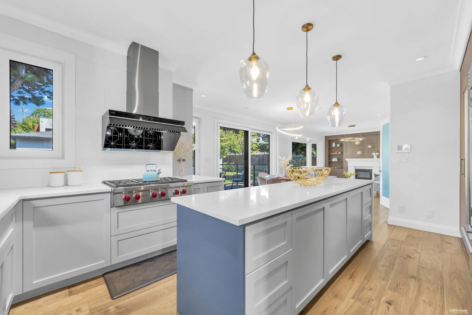 The kitchen with its gas range, wall hood and island, the family room beyond