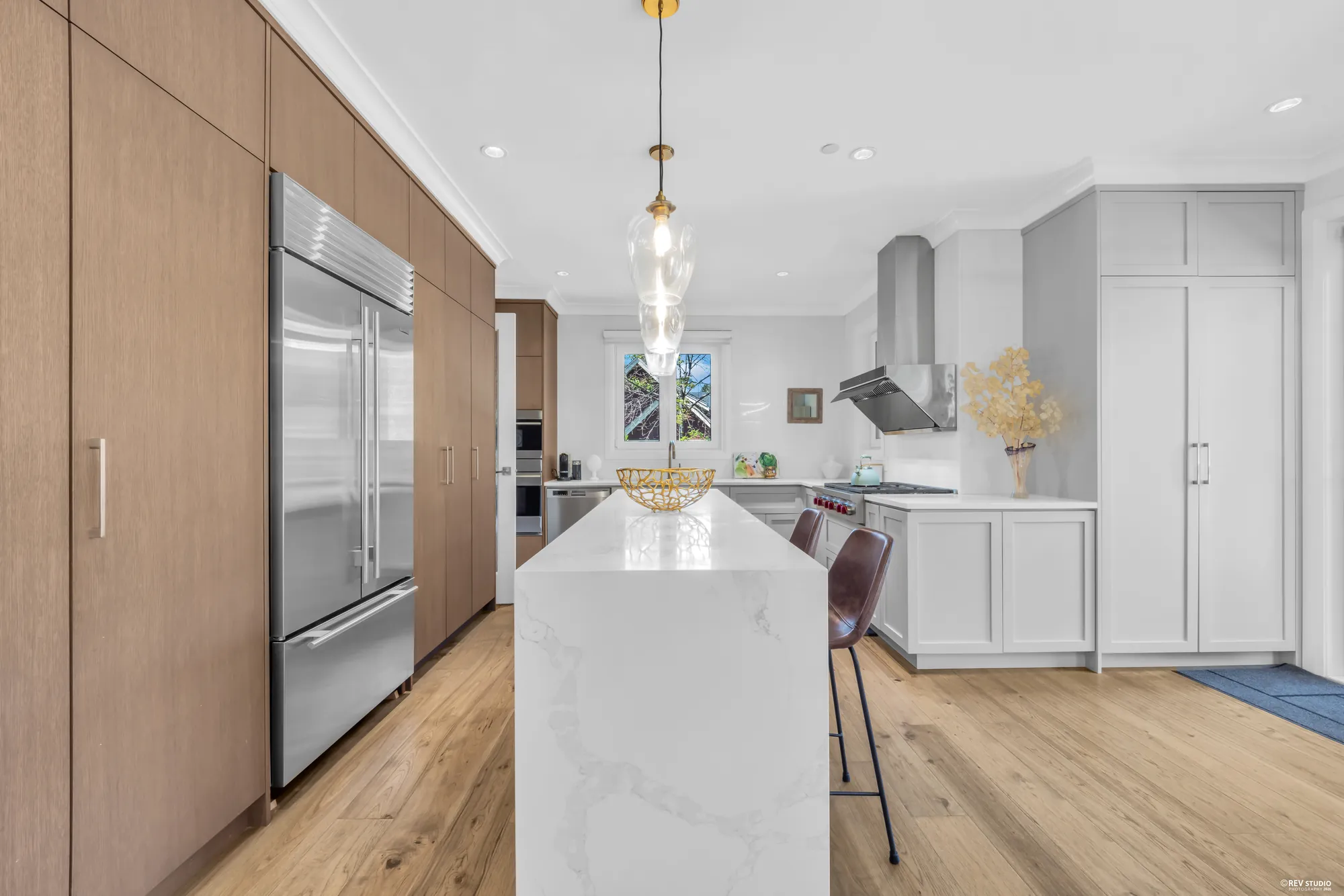 The kitchen island in white stone with the tall cabinet wall behind