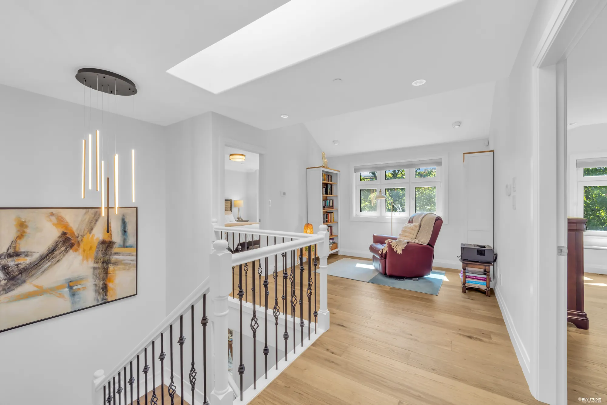 The upper landing under a skylight, black steel balusters along the stairwell