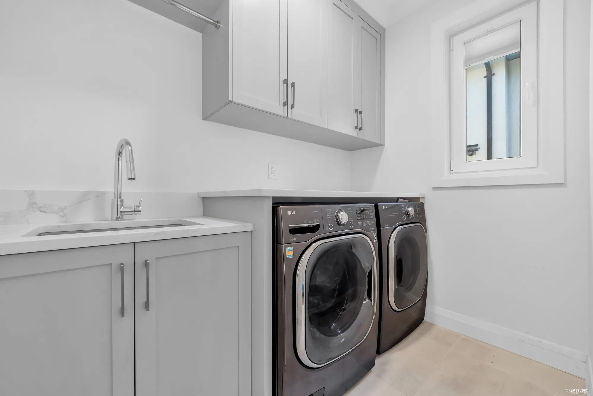 The laundry room with a full-size washer and dryer under a run of cabinets