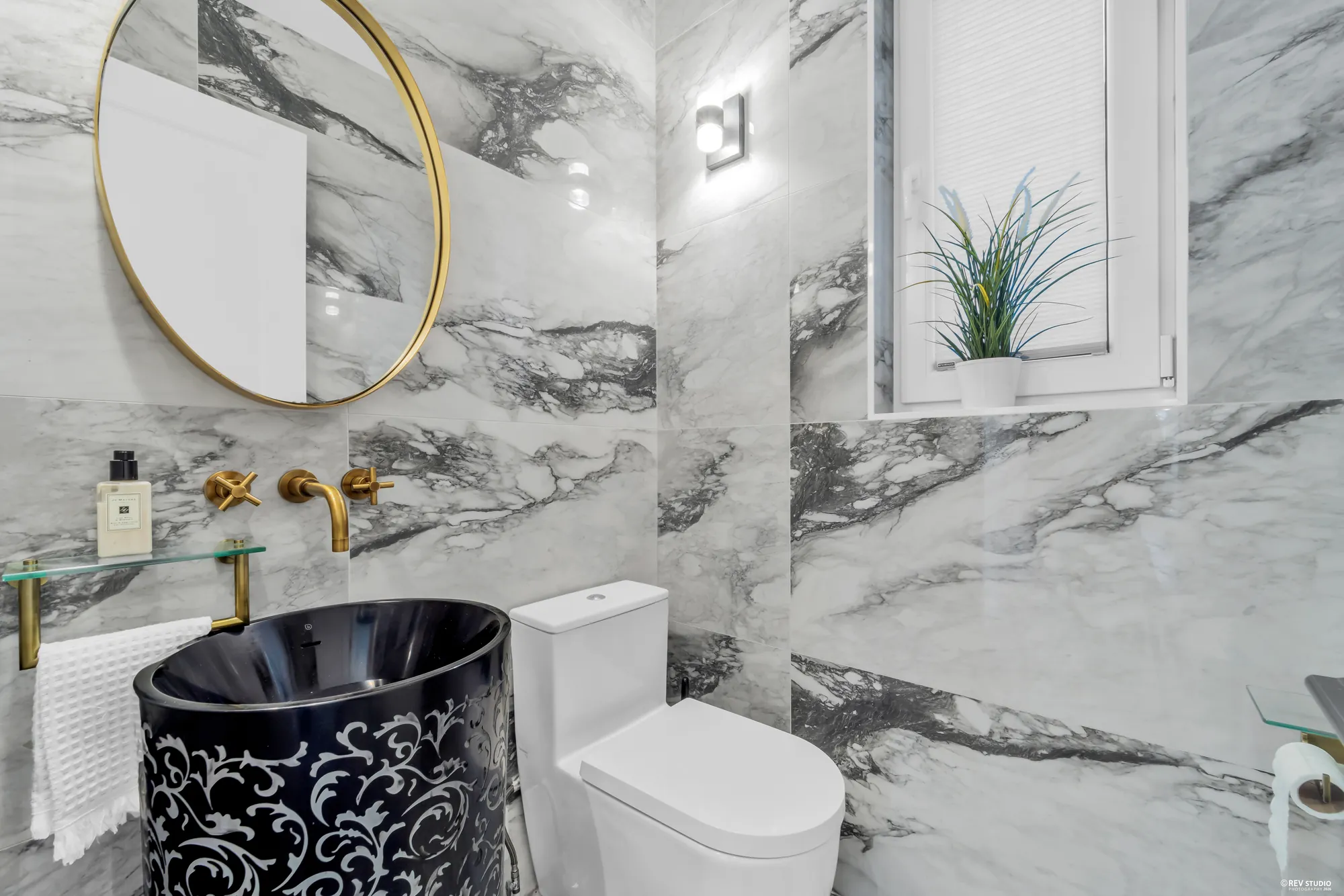 The two-piece bathroom on the main floor, marble walls and a black basin
