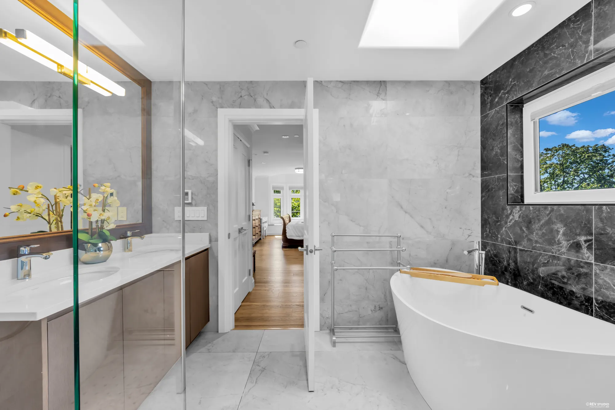 The primary bathroom with a freestanding tub against a black marble wall