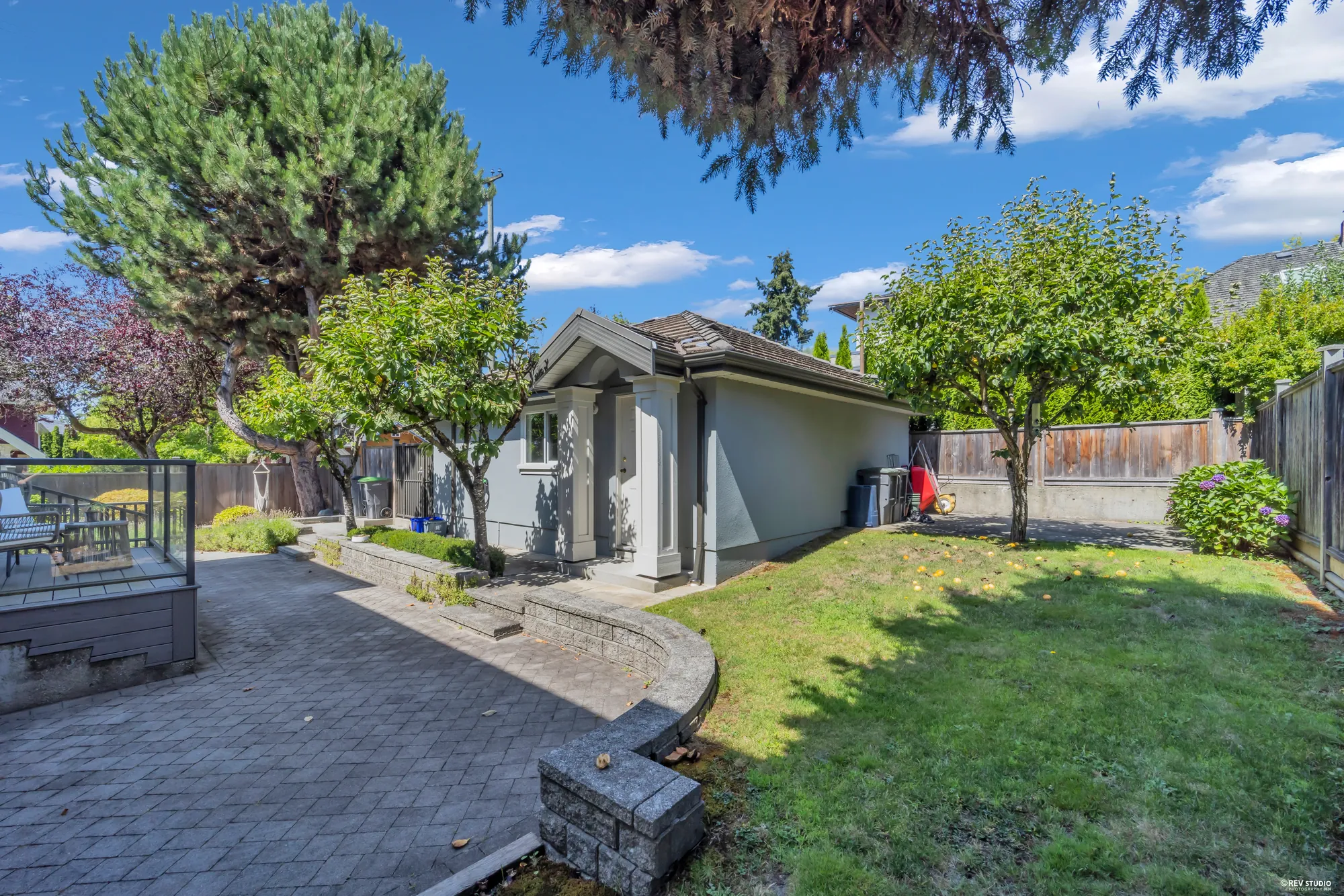 The back garden, paved terrace and lawn, with the garage beyond
